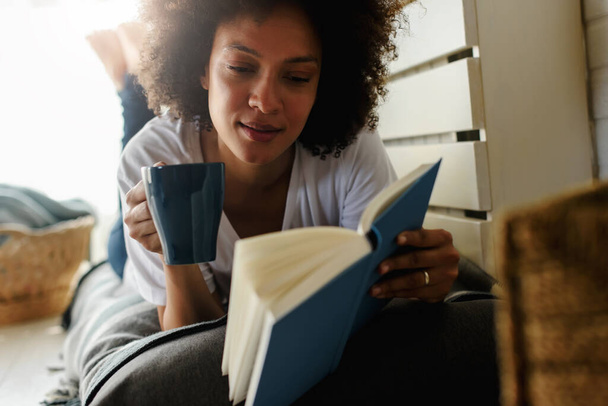 Αφροαμερικανή γυναίκα διαβάζει βιβλία στο σπίτι - Φωτογραφία, εικόνα