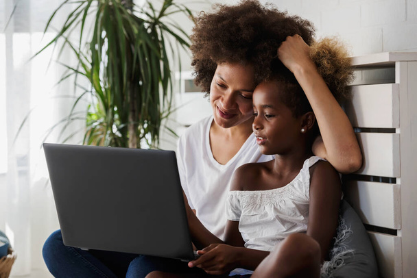 african american mother and daughter using laptop - Foto, afbeelding