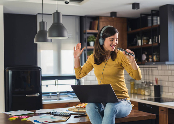 Young smiling woman with headphones working from home, taking break listening music and singing. Positive emotions. Woman with positive attitude. - Foto, Imagem