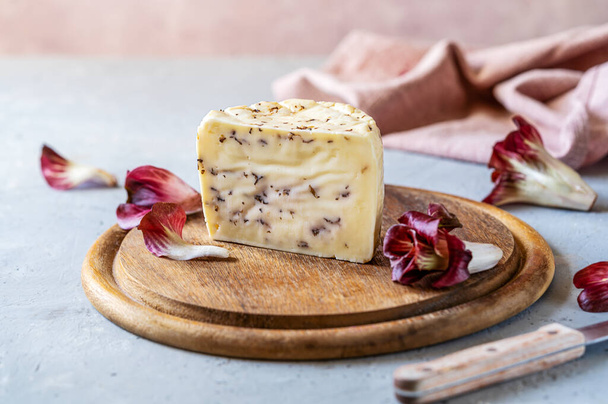 Italian traditional soft cheese Caciotta with radicchio on wooden cutting board, grey and rose background, rose napkin, fresh radish. Traditional artisan Italian cuisine - Fotó, kép