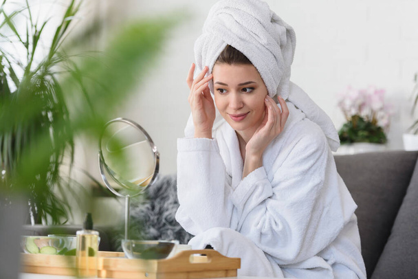 Portrait of a young beautiful woman wearing a bathrobe at home. doing her daily skincare routine with natural cosmetics - Photo, Image