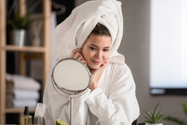 Porträt einer jungen schönen Frau, die zu Hause einen Bademantel trägt. Ihre tägliche Hautpflege mit Naturkosmetik - Foto, Bild