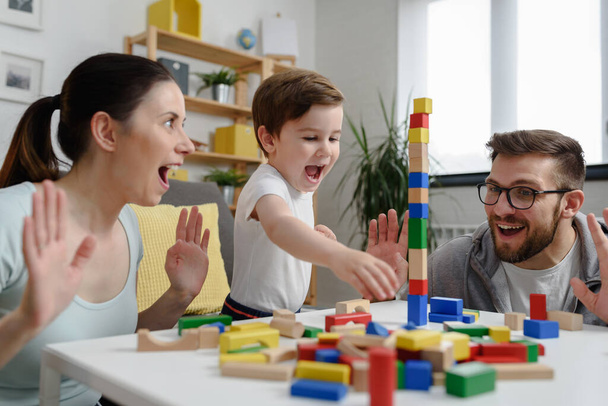 Młoda, szczęśliwa rodzina. Matka i ojciec bawiący się z jej cute maluch syn w domu za pomocą dydaktycznych drewnianych zabawek. Edukacja domowa - Zdjęcie, obraz