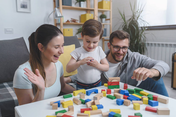 jong gezin spelen met speelgoed houten blokken thuis - Foto, afbeelding