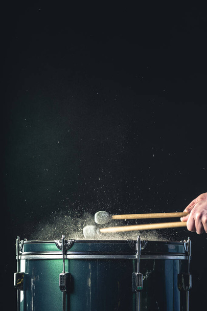 Il percussionista suona con bastoni sul pavimento tom sotto illuminazione in studio.. Concetto di concerto e performance. - Foto, immagini