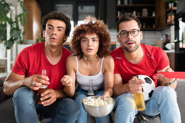 Grupo multiétnico de jóvenes divirtiéndose, viendo un partido de fútbol en la televisión - Foto, Imagen