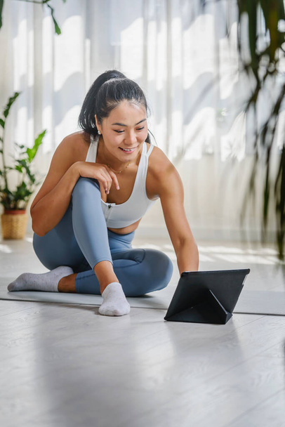 Junge asiatische Yogalehrerin mit Tablet-PC in einem Online-Yoga-Kurs - Foto, Bild