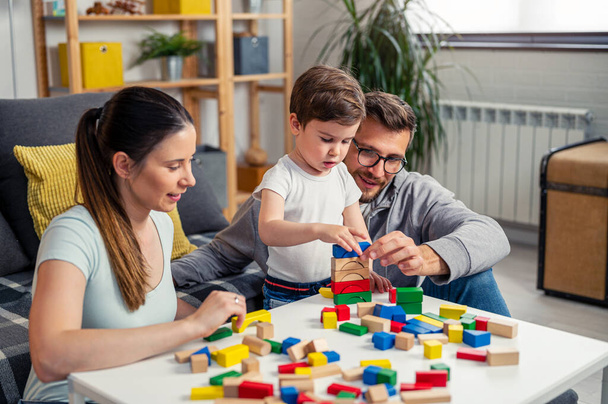 young family playing with toy wooden blocks at home - Foto, Bild