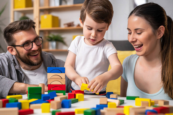 молодая семья играет дома с игрушечными деревянными блоками - Фото, изображение