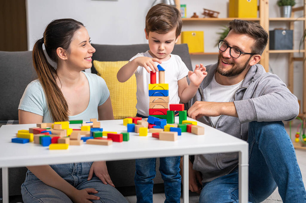 young family playing with toy wooden blocks at home - Foto, Imagen