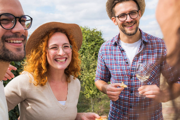 boldog barátok bort isznak a szőlőskertben - Fotó, kép