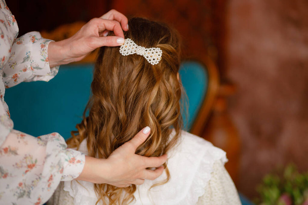 A mother makes her daughter's hairstyle for her long hair. White hairpin. Mother's Day - Fotoğraf, Görsel