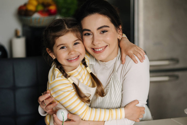 Close-up portret van dochter met moeder in de keuken. Mooie meisjes gekleed in schort. Hoge kwaliteit foto - Foto, afbeelding