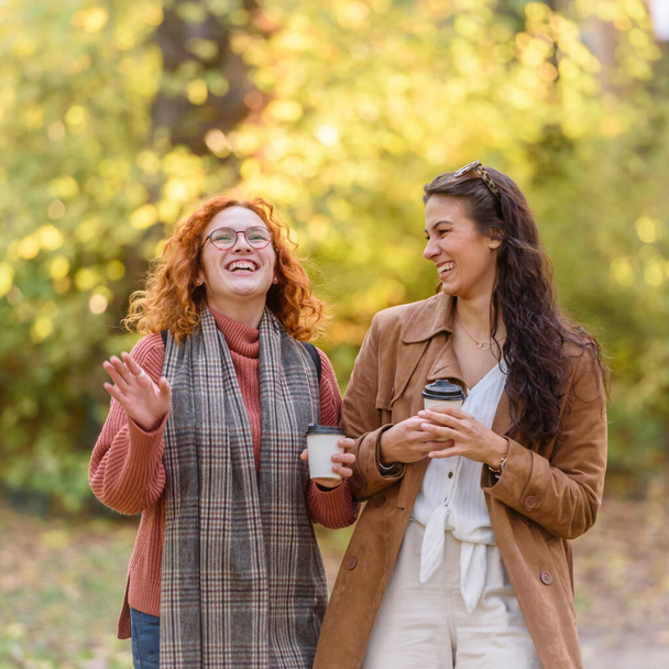 two beautiful women walking outdoors with coffee - Photo, Image