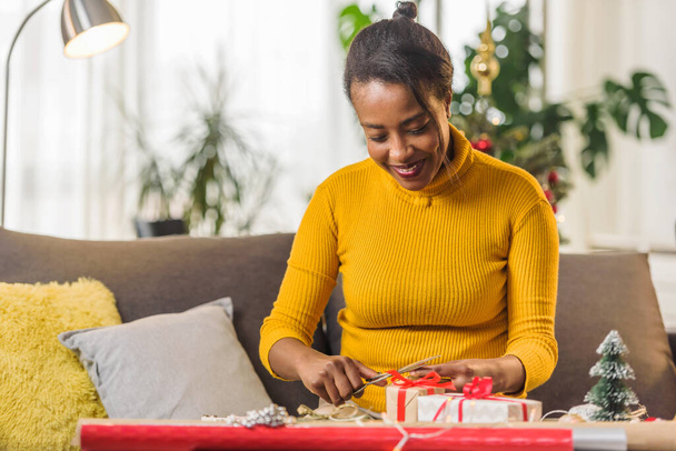 Африканская американка готовится к праздникам, упаковывая подарки - Фото, изображение