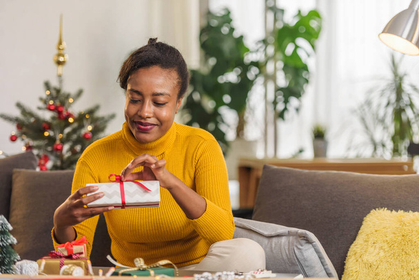 african american woman preparing for holidays, wrapping gifts - Photo, Image