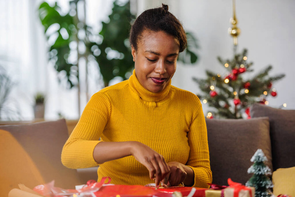 african american woman preparing for holidays, wrapping gifts - Fotografie, Obrázek