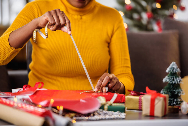 african american woman preparing for holidays, wrapping gifts - Foto, Bild
