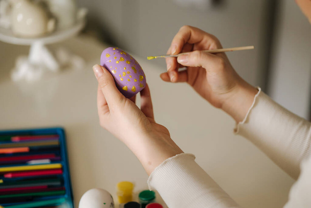 Close-up of woman painting Easter eggs in the kitchen. Spring holidays. High quality photo - Foto, Imagen