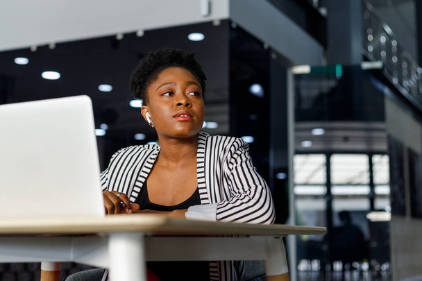 Весела афроамериканка молода жінка професійно сміється і дивиться, працюючи в сучасному корпоративному офісі
 - Фото, зображення