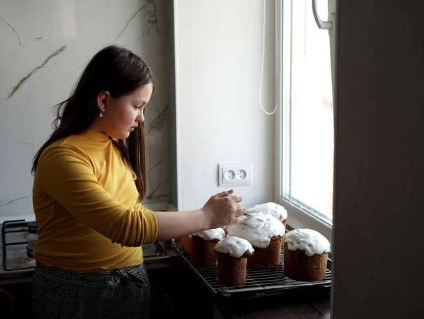 Λευκή γυναίκα αποκωδικοποιεί φρεσκομαγειρεμένα πασχαλινά κέικ. Μαγείρεμα χειροποίητα παραδοσιακά κέικ Πάσχα - Φωτογραφία, εικόνα