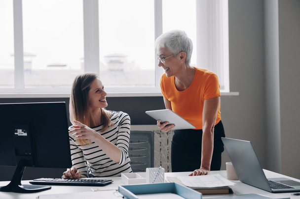 Two happy women discussing business while working in the office together - Photo, Image