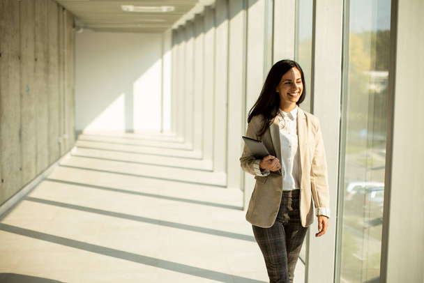 Mladá podnikatelka kráčí po moderní kancelářské chodbě za slunečného dne - Fotografie, Obrázek