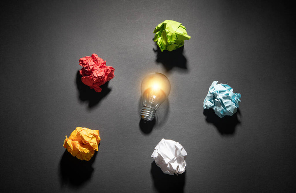 Colorful paper balls and light bulb on the black background. - Photo, Image