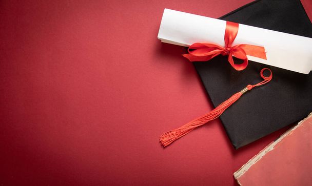 Καπέλο αποφοίτησης και δίπλωμα σε μπορντώ φόντο. - Φωτογραφία, εικόνα