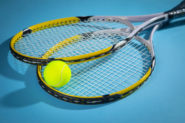 Pelota de tenis y raquetas en el fondo azul. - Foto, imagen