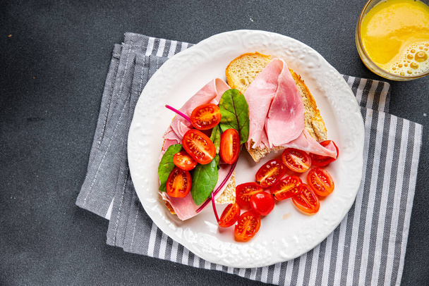 Σάντουιτς ζαμπόν, ντομάτα, μαρούλι μπρουσκέτα σνακ έτοιμο να φάει υγιεινό γεύμα σνακ στο τραπέζι αντίγραφο χώρο τροφίμων φόντο ρουστίκ πάνω όψη - Φωτογραφία, εικόνα