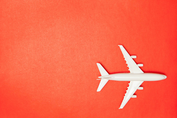 Airplane model. White plane on red background. Travel vacation concept. Summer background. Flat lay, top view, copy space. - Foto, imagen