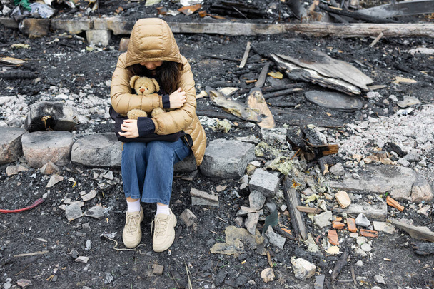 A girl next to a house destroyed by the war. War in Ukraine. Ukrainian refugees. Child in the ruins of his house destroyed by the war. Peace concept - Photo, Image