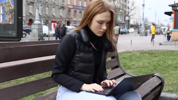 bella studentessa testa rossa utilizzando computer portatile nel parco - Filmati, video