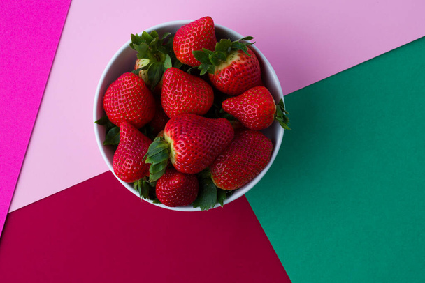 tazón blanco con fresas sobre fondo de color plano laico - Foto, imagen
