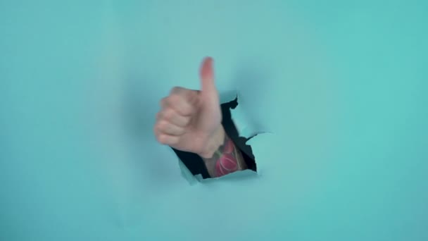 showcases a tumb up tatooed hand isolated on blue background. High quality 4k footage - Footage, Video