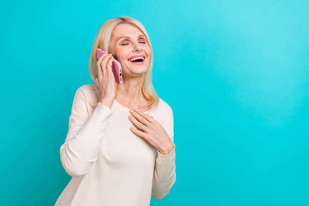 Photo of retired businesswoman wear stylish casual shirt hold phone calling her employee laughing funny joke isolated on aquamarine color background. - Фото, зображення
