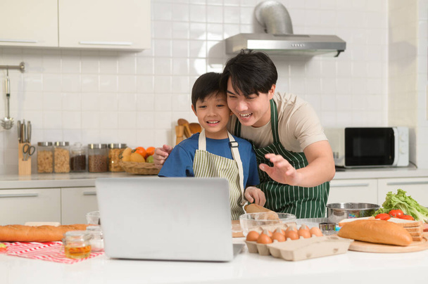 Happy smiling Young Asian father and son making video call to mother. enjoy cooking in kitchen at home - Φωτογραφία, εικόνα