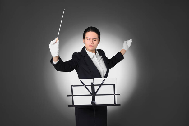 Professional conductor with baton and note stand on grey background - Foto, Imagen