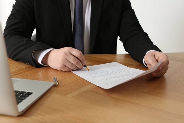 Notary signing document at wooden table, closeup - Fotó, kép