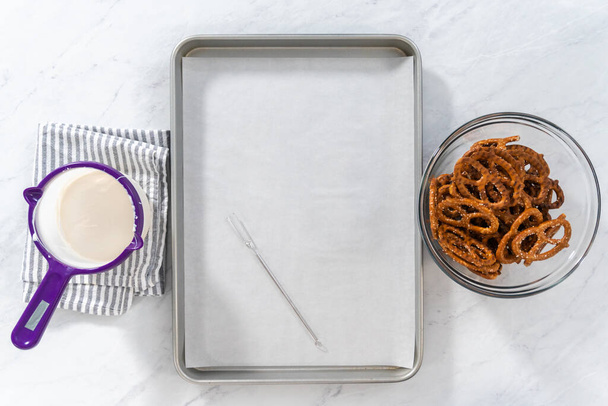 Flat lay. Dipping pretzels twists into melted chocolate to make chocolate-covered pretzel twists. - Photo, Image