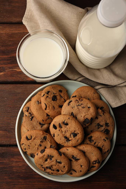 Delicious chocolate chip cookies and milk on wooden table, flat lay - Photo, image