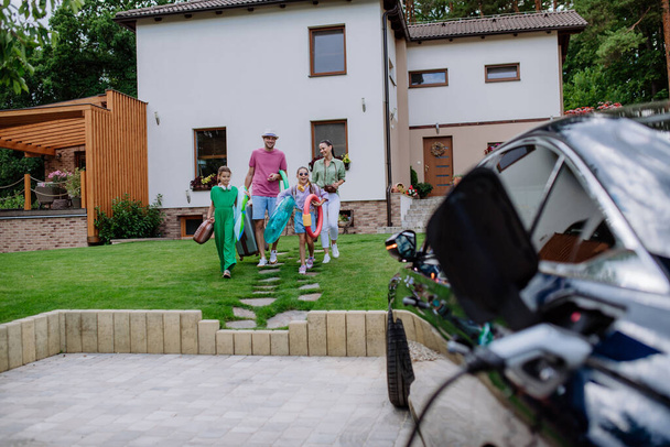 Happy family preparing for a holiday while their electric car charging. - Valokuva, kuva