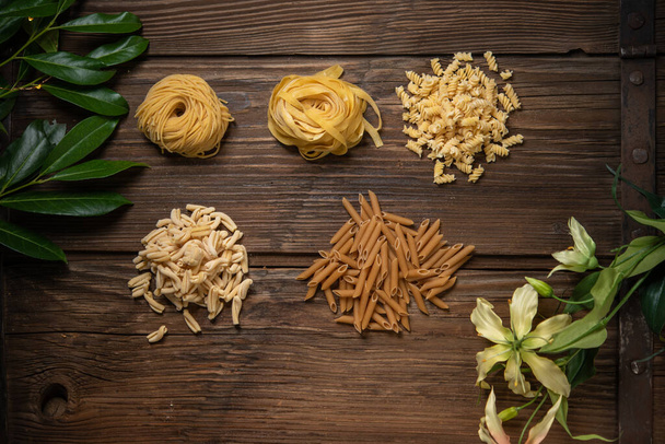 top view of raw uncooked dry pasta on wooden board - Foto, Imagem