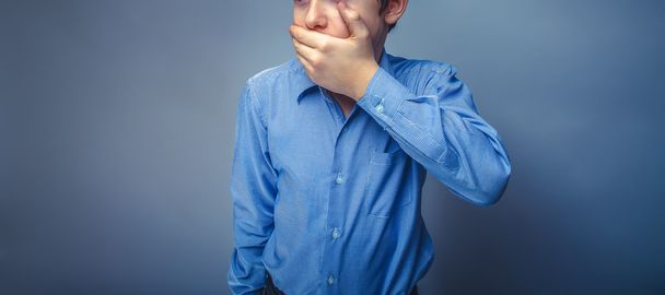Adolescente chico europeo apariencia marrón pelo mano cerrado boca siente
 - Foto, Imagen