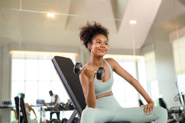 Sporty fitness African American woman working out with dumbbells strength and strength endurance at the gym - Foto, Imagem
