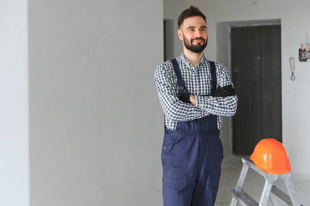 smiling repairman standing near stepladder and looking at camera. - 写真・画像