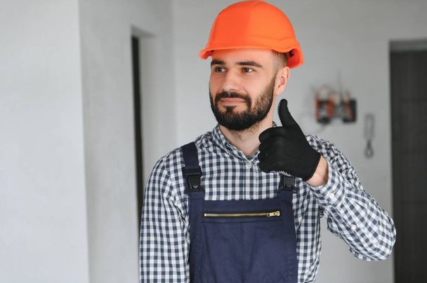 Portrait of positive, handsome young male builder in hard hat. - 写真・画像