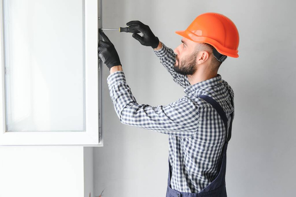 Worker in installing white plastic upvc window on house - Photo, Image