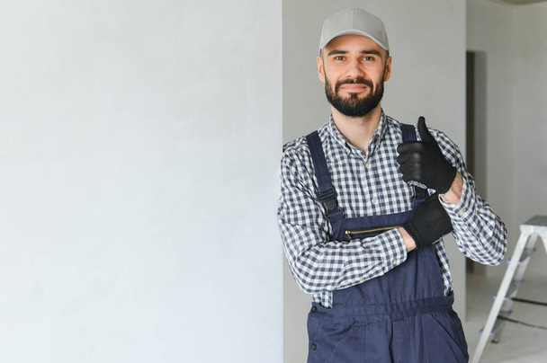 smiling repairman standing near stepladder and looking at camera. - Foto, afbeelding